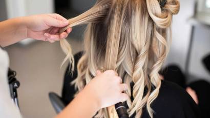 Studija ONE Beauty, frizieris veido lokas sievietei ar blondiem matiem.