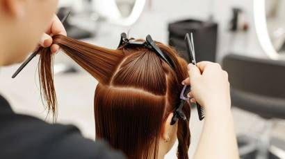 Studija ONE Beauty, frizieris griez sievietes matus, sadalot tos sadalas ar matu skavam.